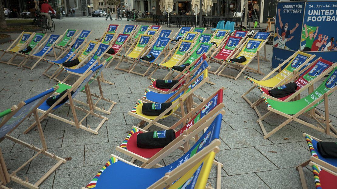 Viele leere Camping-Stühle stehen auf einem Platz in Stuttgart. Auf manchen Stühlen liegen schwarze Decken. 