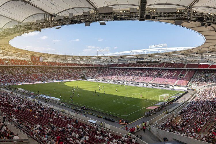 Das Fußball-Stadion in Stuttgart von innen. In der Mitte ist das Fußball-Feld. Um das Fußball-Feld sitzen sehr viele Menschen. 